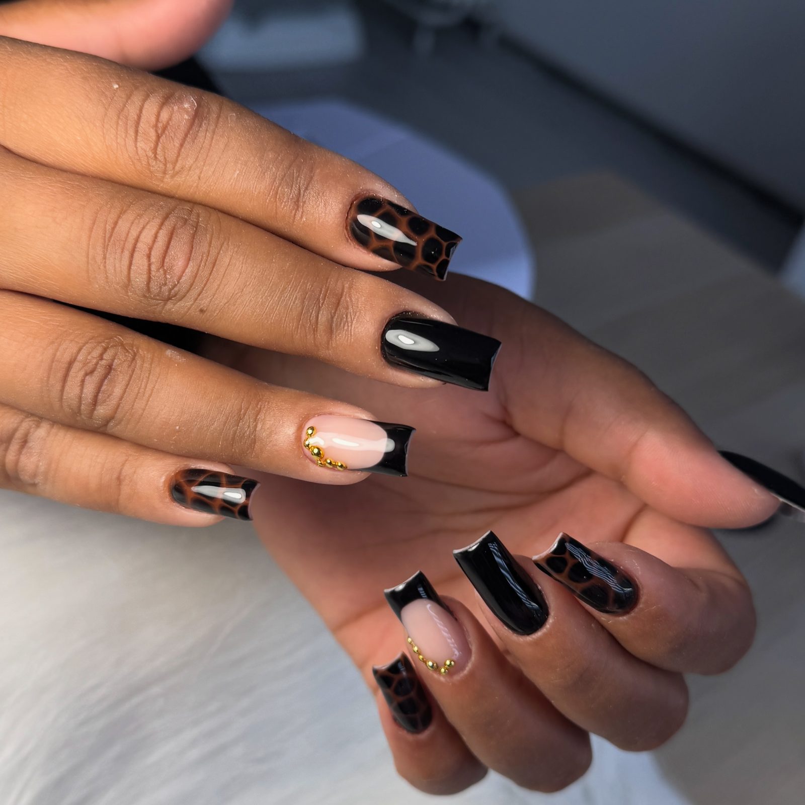 Vierkante nagels in zwart met tortoise-print en gouden details